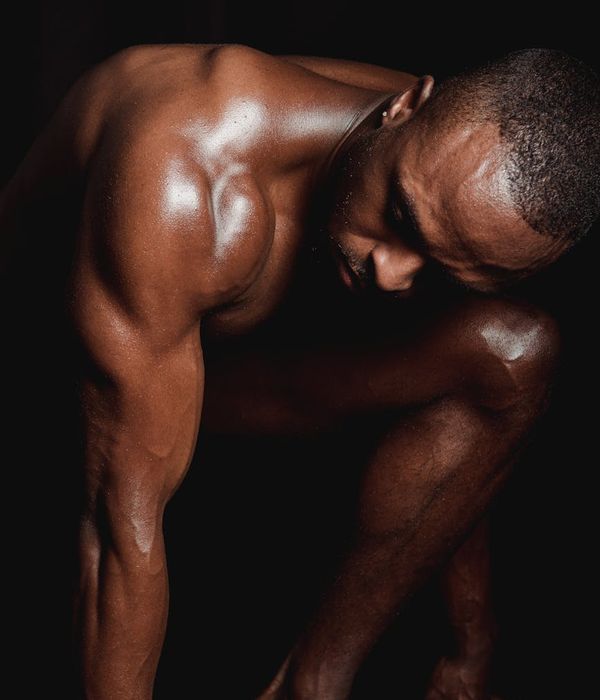 Man performing a powerful strength exercise in a dark gym.